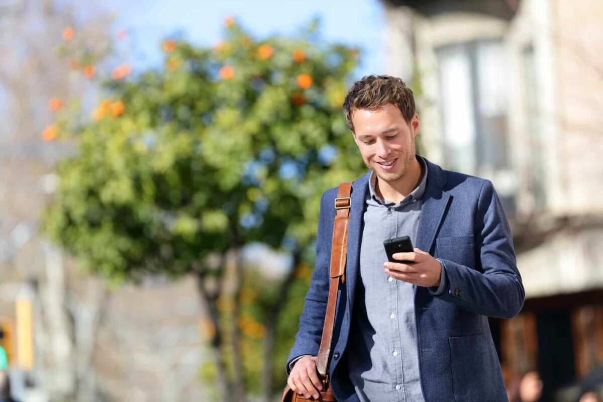 A process server outdoors checks his phone, representing the crucial role of technology in enhancing verification and efficiency in his work.