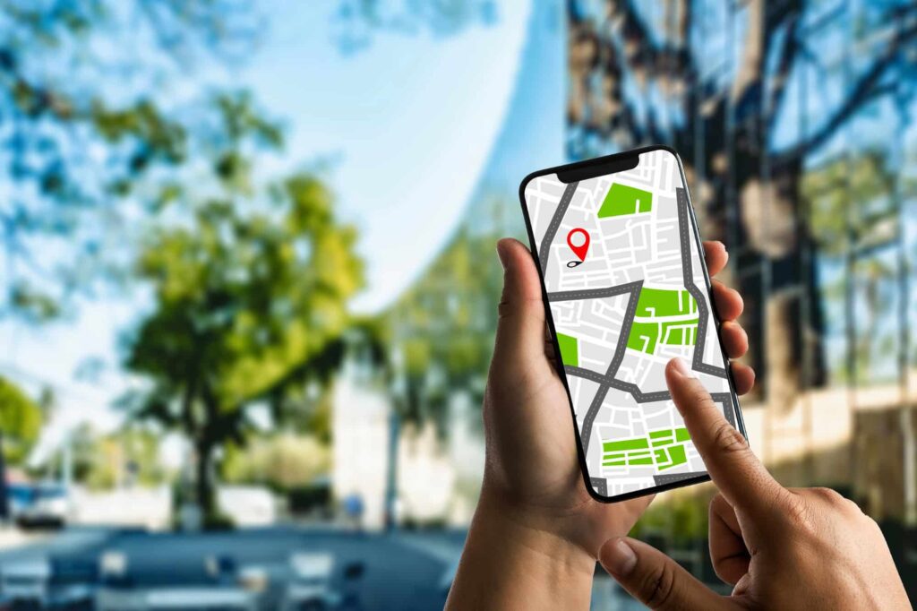 A process server with a smartphone showing a GPS map, standing outside a building entrance.